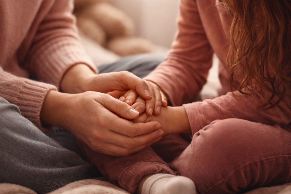 mamma che stringe le mani della figlia come supporto emotivo.