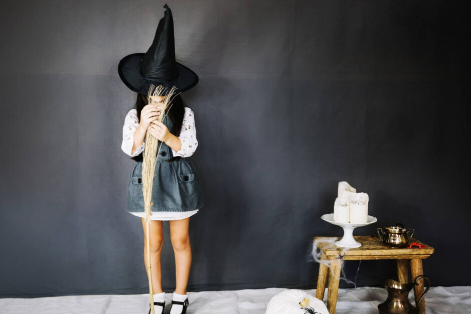 bambina con un capello da strega nero che impugna una scopa