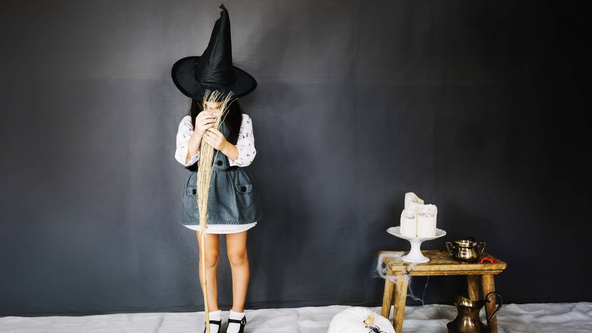 bambina con un capello da strega nero che impugna una scopa