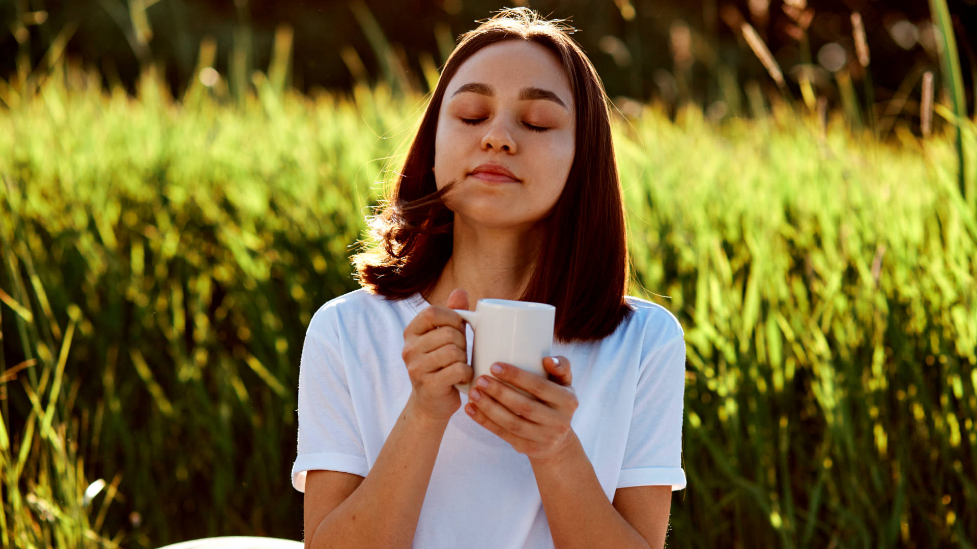 Ragazza in un giardino che si ralassa bevendo un atazza di te