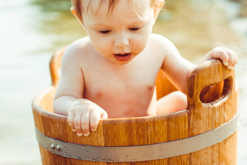 bambino immerso in un secchio pieno d'acqua