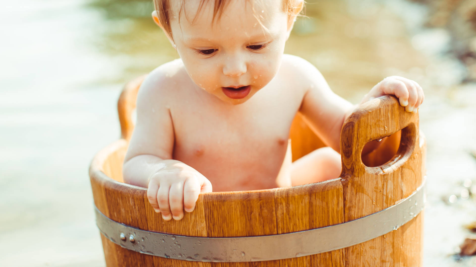 bambino immerso in un secchio pieno d'acqua