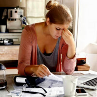 Mamma perplessa davanti a scartoffie e computer.