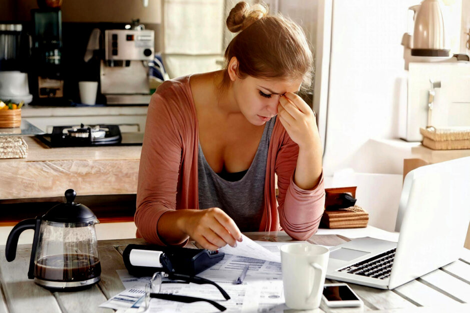 Mamma perplessa davanti a scartoffie e computer.