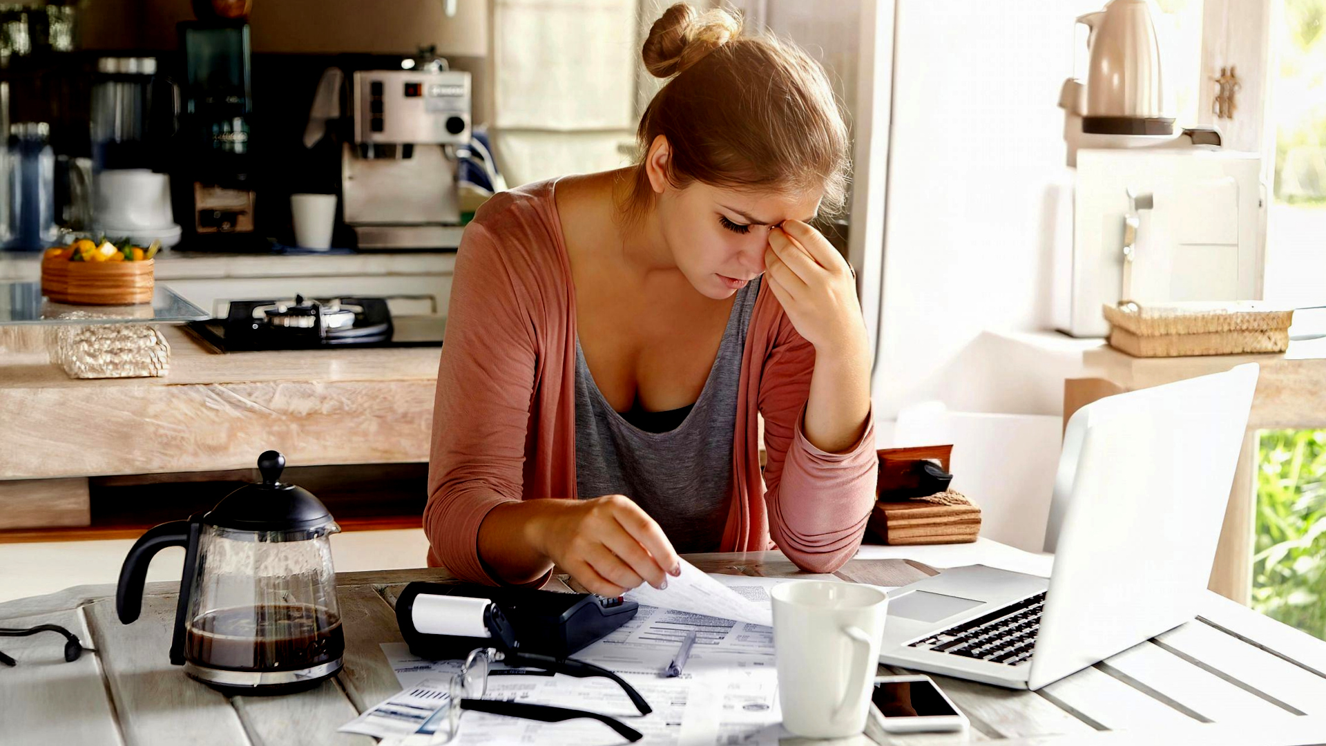 Mamma perplessa davanti a scartoffie e computer.