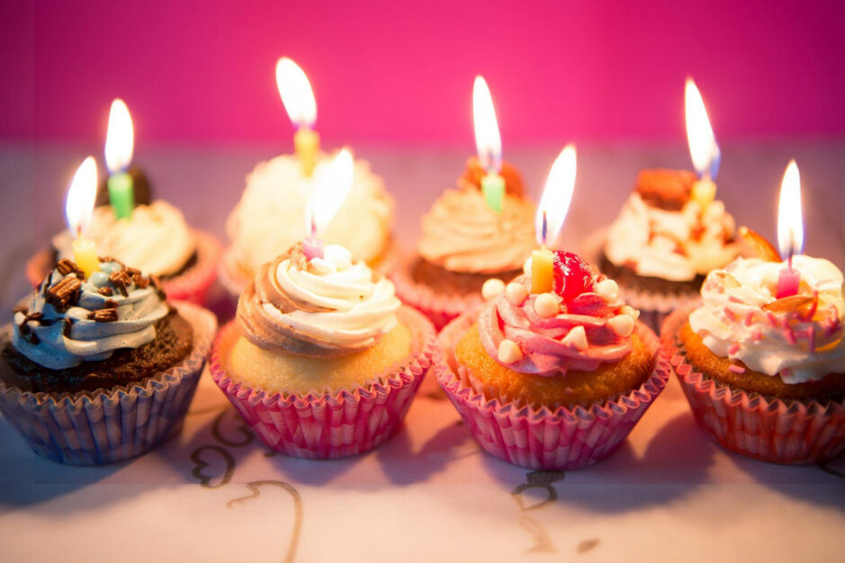 Tavolata di muffin con candeline di compleanno accese.