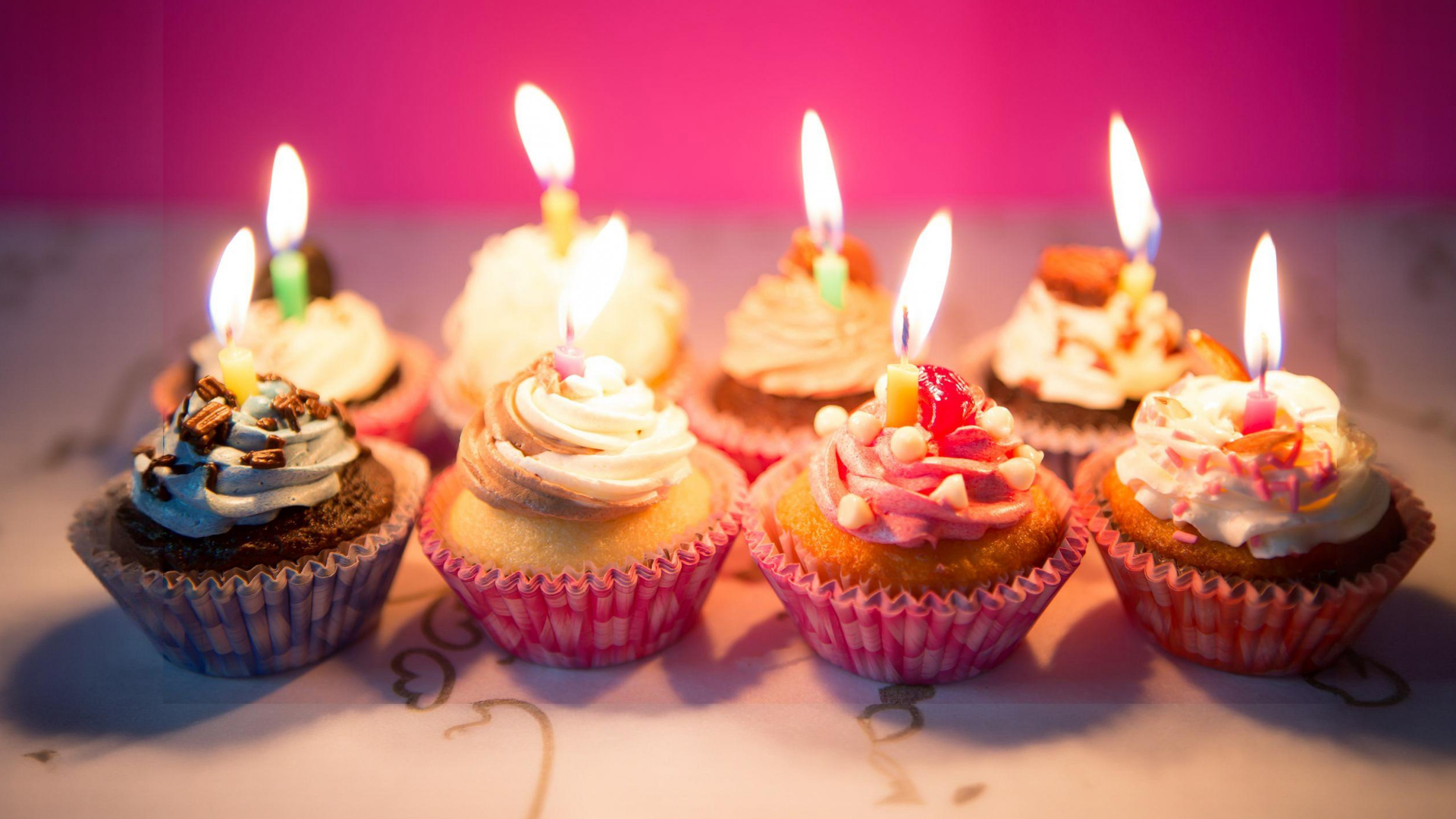 Tavolata di muffin con candeline di compleanno accese.