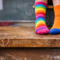 Piedi con calzini spaiati seduti sul banco con scritta brutto.