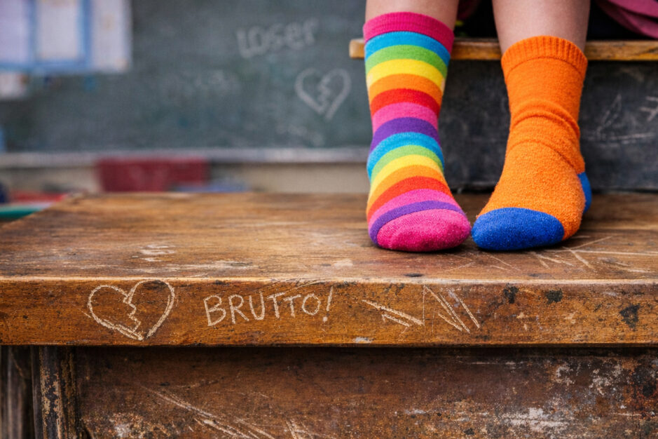 Piedi con calzini spaiati seduti sul banco con scritta brutto.