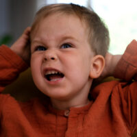 Volto di un bambino che fa una smorfia arrabbiato.