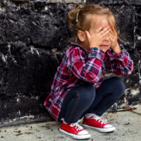 bimba che piange contro un muro