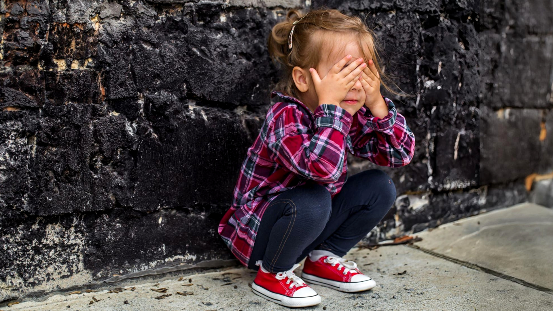 bimba che piange contro un muro