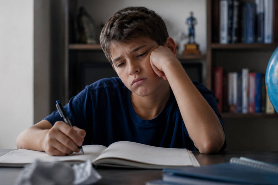 Ragazzo demotivato che scrive su di un libro di scuola