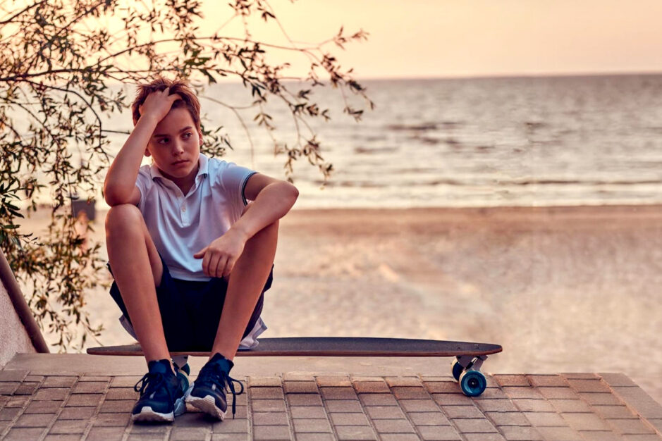 adolescente annoiato seduto su di uno skateboard