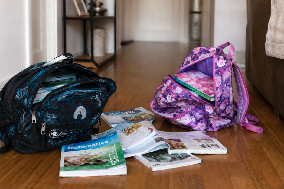 due zaini di scuola con alcuni libri di scuola lasciati sul pavimento di casa