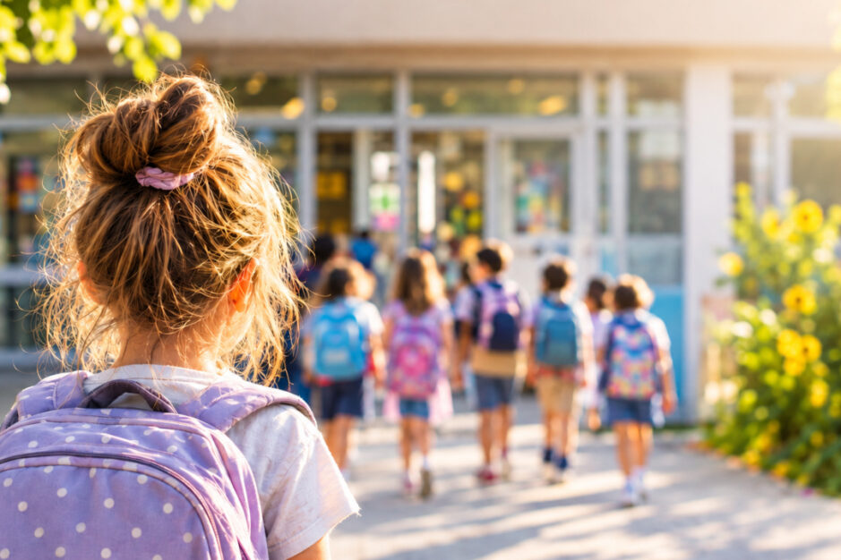 Bambina che guarda altri bambini entrare a scuola